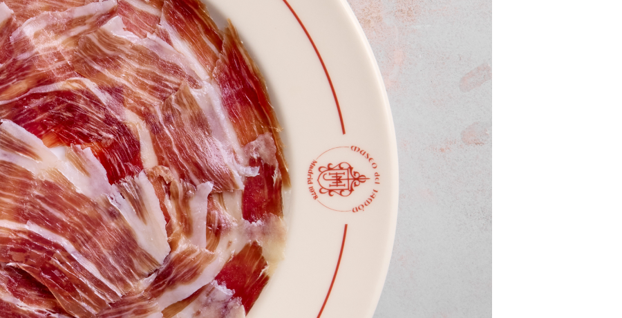 Lonchas de jamón ibérico en un plato, cortadas finas y con vetas de grasa infiltrada.