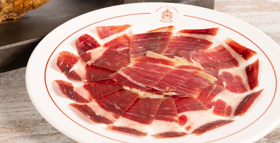 Plato con finas lonchas de jamón ibérico, resaltando su color rojo intenso y el veteado de grasa