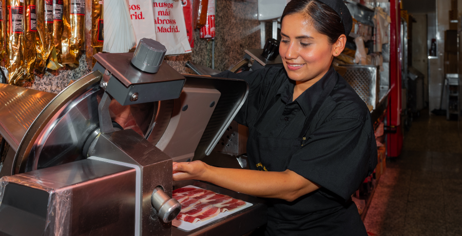 Profesional cortando jamón en máquina cortadora obteniendo lonchas finas listas para servir