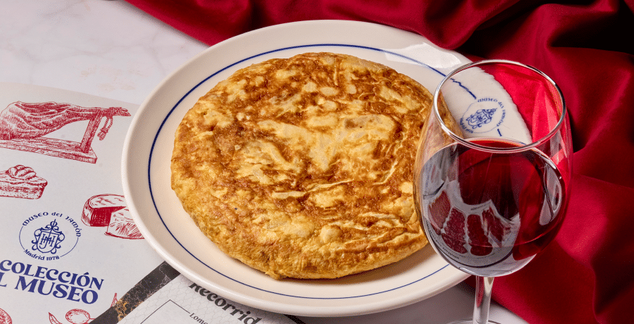 Tortilla española servida en plato de Museo del Jamón junto a una copa